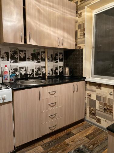 a kitchen with wooden cabinets and a sink at Однокомнатная квартира in Shymkent