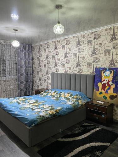 a bedroom with a bed with a blue comforter at Однокомнатная квартира in Shymkent