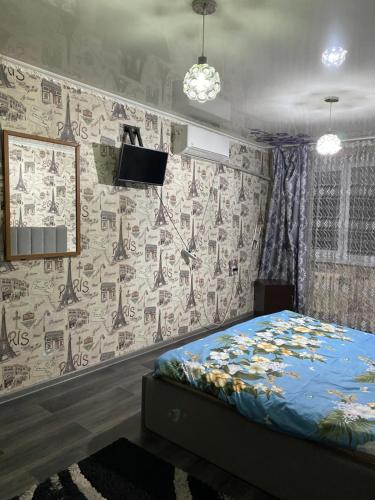 a bedroom with a bed and a wall with wallpaper at Однокомнатная квартира in Shymkent