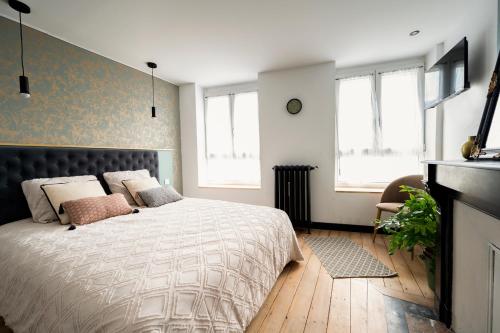 een slaapkamer met een bed en 2 ramen bij Élégante chambre avec salle de douche privative in Montivilliers