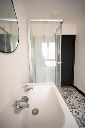 une salle de bain blanche avec un lavabo et un miroir dans l'établissement Élégante chambre avec salle de douche privative, à Montivilliers