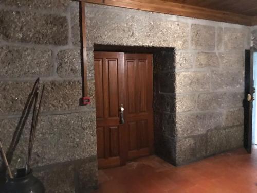 uma parede de tijolos com uma porta de madeira num quarto em CASA AUGUSTA HOTEL - QUINTA em Penafiel