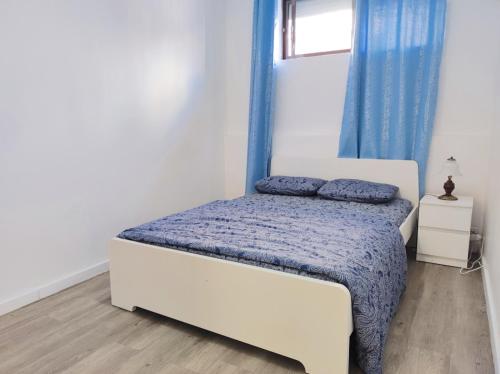 a bedroom with a white bed with blue sheets and a window at laxuries Room for rent in Odivelas