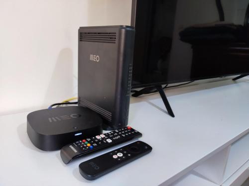 a computer monitor with two remote controls on a desk at laxuries Room for rent in Odivelas