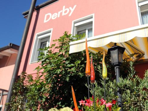 Hotel Derby Interlaken - Action & Relax Hub في إنترلاكن: مبنى وردي أمامه مظلة