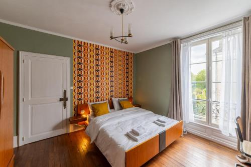 a bedroom with a large bed and a large window at Villa du Loir in La Flèche