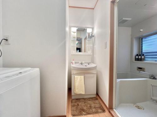 a white bathroom with a sink and a bath tub at AX-Asaka House in Asaka