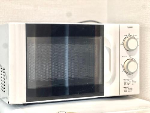 a white microwave oven sitting on top of a counter at AX-Asaka House in Asaka