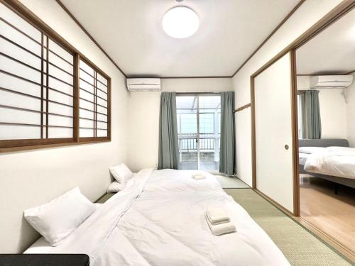 a large white bed in a room with a window at AX-Asaka House in Asaka