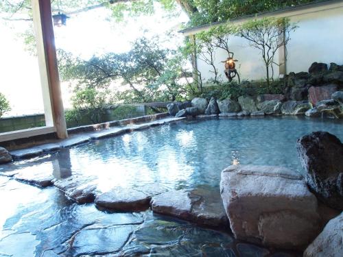 a large swimming pool with rocks in a backyard at Senkei in Hakone