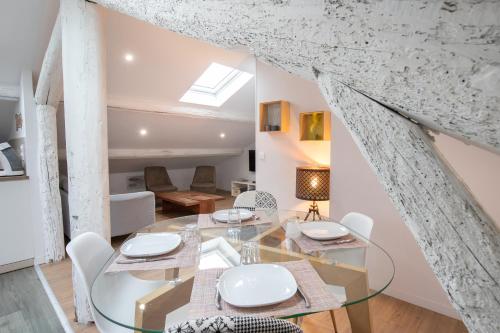 une salle à manger avec une table en verre et des chaises blanches dans l'établissement La Chic Comédie - 2 chambres - hypercentre - Wifi, à Montpellier