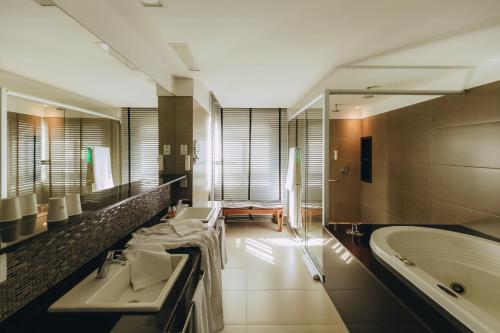 ein großes Badezimmer mit zwei Waschbecken und einer Badewanne in der Unterkunft Golden Tulip Natal Ponta Negra in Natal