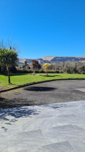 um parque de estacionamento vazio com árvores e um campo em castle Road House em Castletownbere