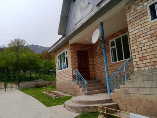 ein Backsteinhaus mit einer Treppe und einer Tür in der Unterkunft Guest house Tan Nuru Sary-Chelek in Arkit