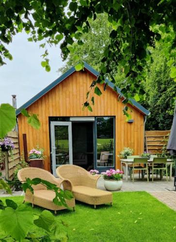 a garden with chairs and a building with a patio at Vakantiehuisje Bellefleur huisje Jasmijn in Roderwolde