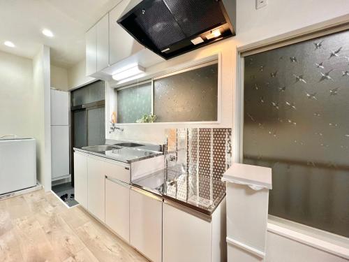 a kitchen with white cabinets and a microwave at AX-Ojima House in Tokyo