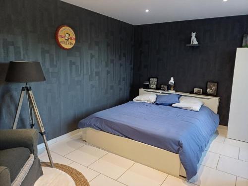 Schlafzimmer mit einem Bett mit blauer Bettwäsche und einem Stuhl in der Unterkunft La Grange des Roisnes in Longué