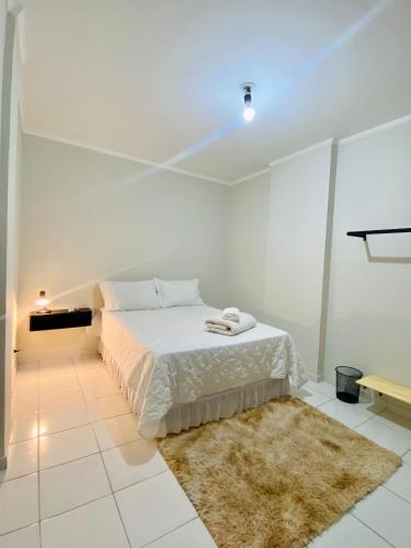 a white bedroom with a bed and a rug at Quarto privativo Velho Chico 2 in Petrolina