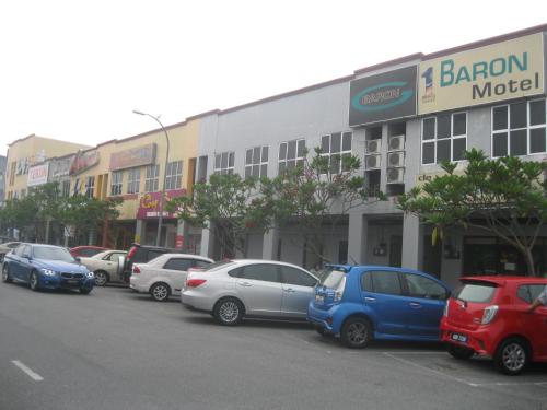 a row of cars parked in a parking lot in front of a building at 1 Baron Motel in Kuah