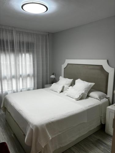 ein weißes Schlafzimmer mit einem großen Bett mit weißen Kissen in der Unterkunft Apartamento Bajondillo Playa y piscina in Torremolinos