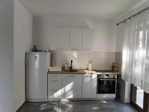 uma cozinha com armários brancos e um frigorífico em Mondeno house em Utjeha