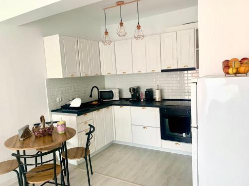 uma cozinha com armários brancos e uma mesa com cadeiras em Apartament 1 camera em Sancraiu de Mures