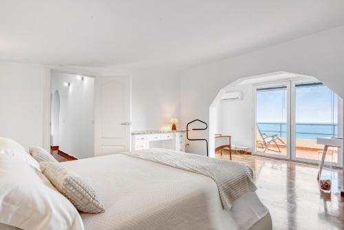 Dormitorio blanco con cama y vistas al océano en Villa Infinity sea views I Pool I BBQ I Jacuzzi, en Almería