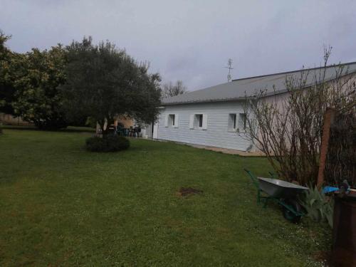 une cour avec une maison blanche et un bâtiment dans l'établissement chambres d'hôtes Le Boisseau, à Saint-Michel-de-Montaigne