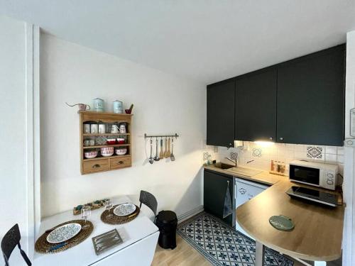 une petite cuisine avec une table et un micro-ondes dans l'établissement Appartement Le petit Génois à port Olona, à Les Sables-dʼOlonne