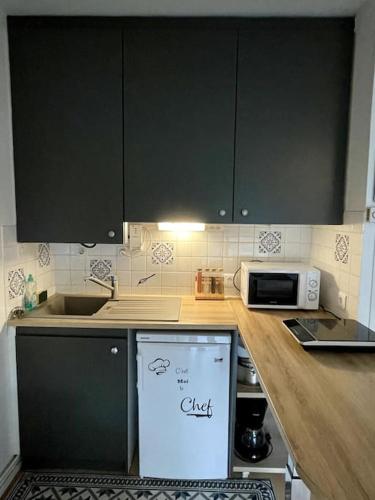 - une cuisine avec des armoires noires et un réfrigérateur blanc dans l'établissement Appartement Le petit Génois à port Olona, à Les Sables-dʼOlonne