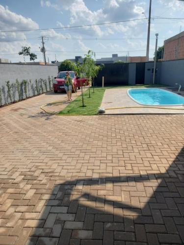 a man standing next to a brickicked driveway with a swimming pool at Wm Milão in Sinop