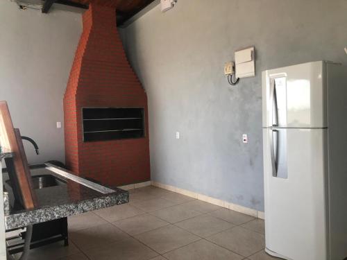 a kitchen with a refrigerator and a brick fireplace at Wm Milão in Sinop