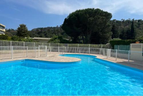 een groot blauw zwembad met een hek bij Appartement calme, cosy Piscine in Mandelieu-la-Napoule