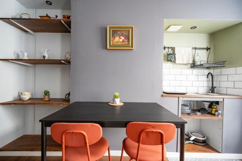 une cuisine avec une table noire et deux chaises oranges dans l'établissement Appartement spacieux et élégant avec jardin, à Montivilliers