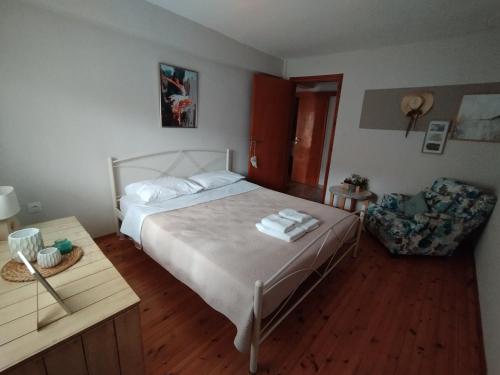 a bedroom with a white bed and a chair at OLYMPUS HILL in Litochoro