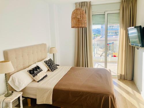 een slaapkamer met een groot bed en een televisie bij Apartamento Las Rotas in Denia