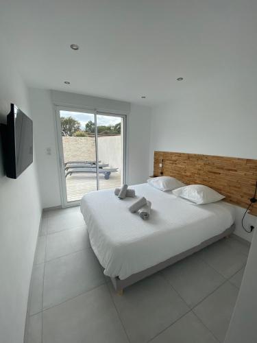 une chambre blanche avec un grand lit et une fenêtre dans l'établissement Villa Santa Giulia, à Porto-Vecchio