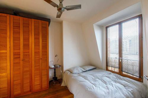 une chambre avec un lit et une grande fenêtre dans l'établissement Paris 5ème - Grand Appartement, à Paris