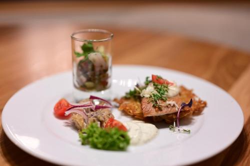 a white plate with food on a wooden table at Altes Kurhaus Landhotel in Trabelsdorf