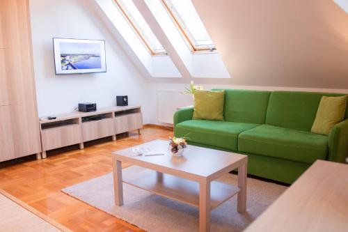 ein Wohnzimmer mit einem grünen Sofa und einem Tisch in der Unterkunft Gárdonyi Apartman in Eger