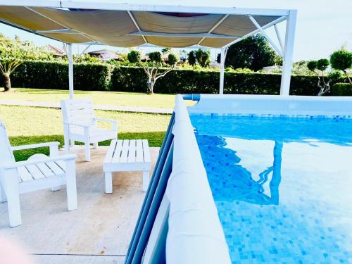 una piscina con due sedie bianche e un ombrellone di Villa Eagle a Terrasini