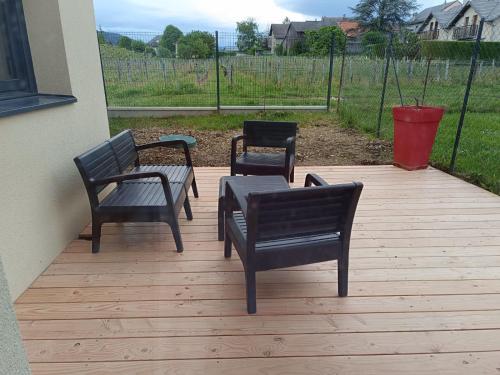 trzy krzesła i stół na drewnianym tarasie w obiekcie Chambre au coeur des vignes w mieście Myans