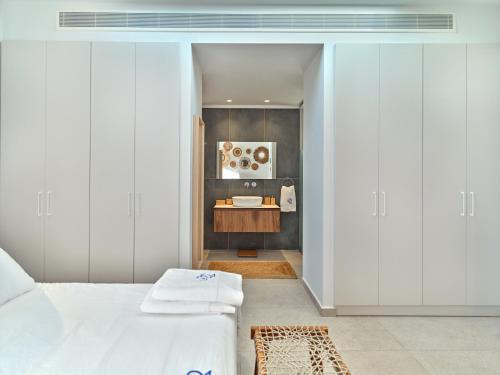 a bedroom with a white bed and a sink at Villa Le22, 180 panoramic sea views, Paros in Kampos Paros