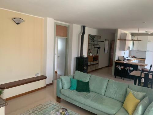 a living room with a green couch and a kitchen at Appartamento Gli Ulivi in Mercato Saraceno