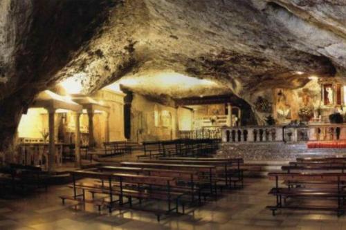 uma igreja com bancos de madeira numa caverna em Art House Centro - Gargano em San Giovanni Rotondo