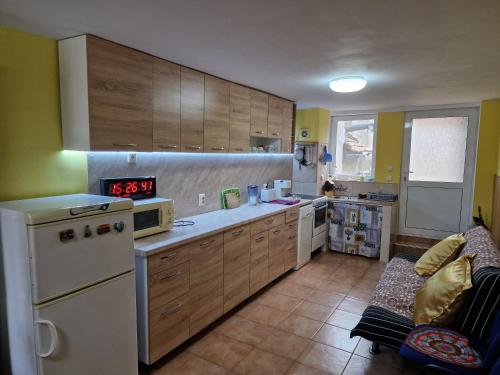 cocina con armarios de madera y nevera blanca en Къща за гости Пантови en Grammatikovo