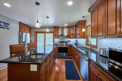 a large kitchen with wooden cabinets and black counter tops at Spacious Catskills Serenity nearby Delaware River Gap w Game Rm Pet Friendly and Fenced Yard in Glen Spey