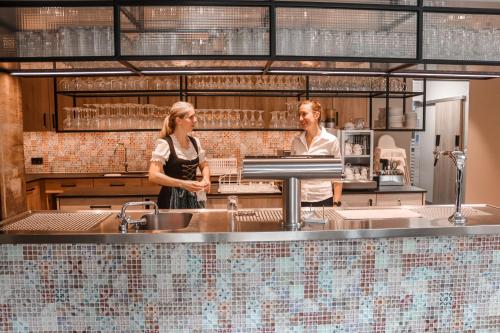 a man and a woman standing in a kitchen at Altes Kurhaus Landhotel in Trabelsdorf