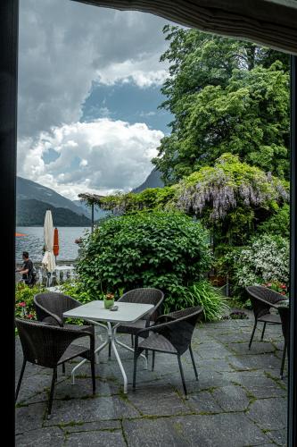 a table and chairs on a patio next to a lake at Hotel Le Prese in Poschiavo