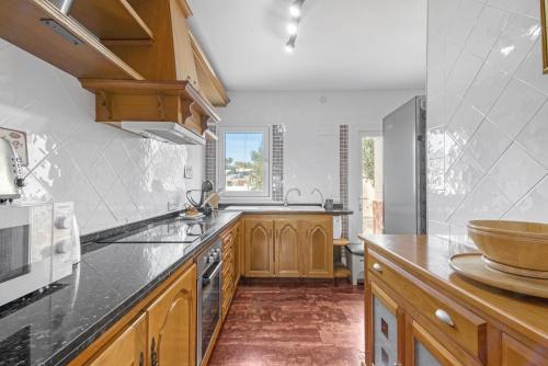 a kitchen with wooden cabinets and a counter top at Villa Infinity sea views I Pool I BBQ I Jacuzzi in Almería